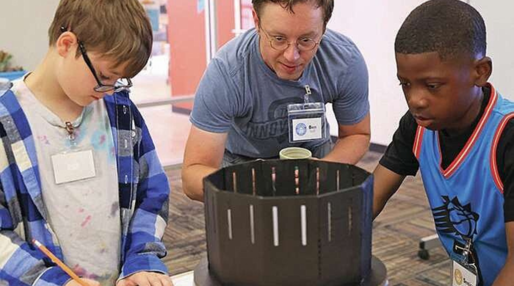 Hub educator Ben Watson works with two summer camp youth participants in building a zoetrope animation device