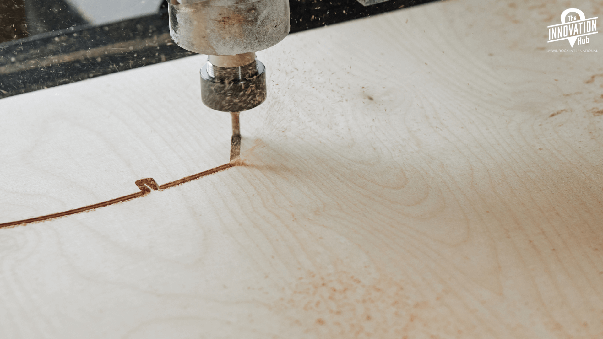 A cnc router, carving into a piece of wood with saw dust around.