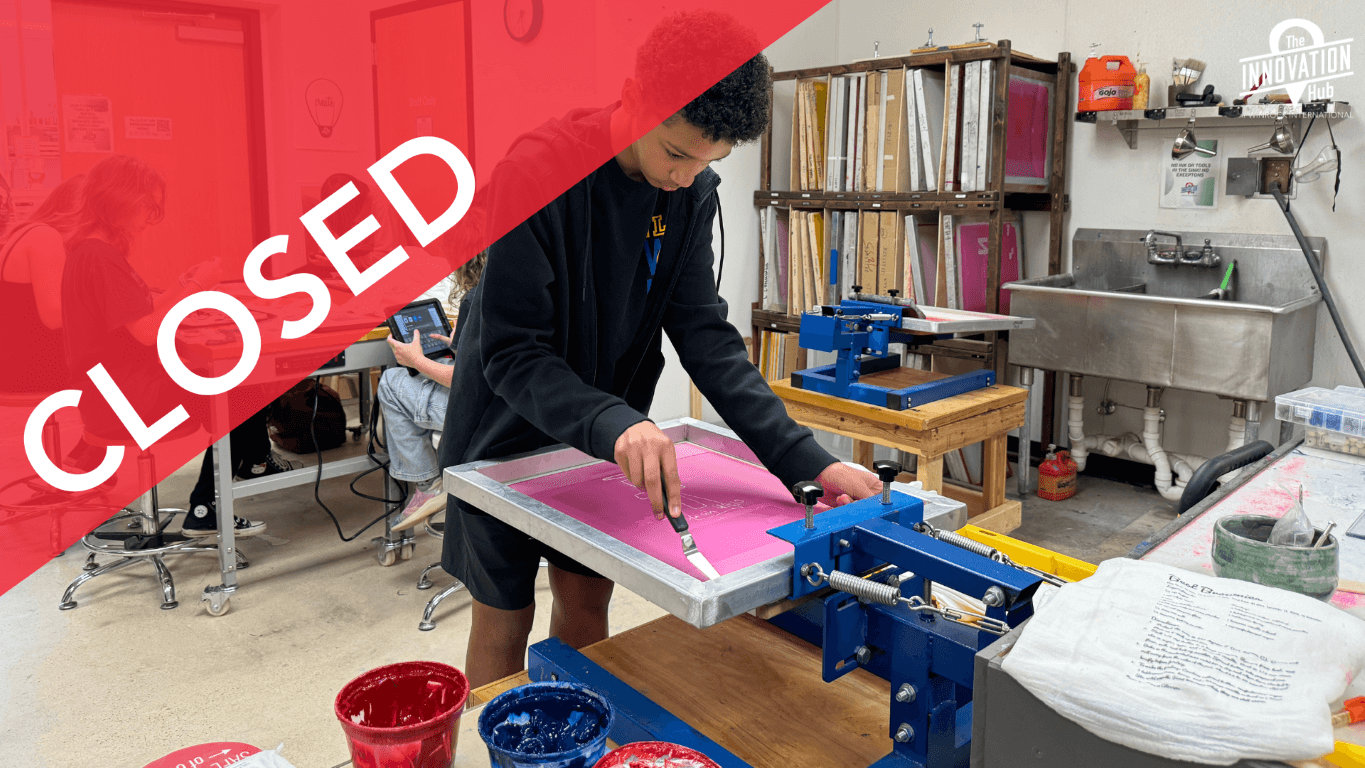 A young boy prepares to screen print a t-shirt that he designed while other after school students work on designs in the background.