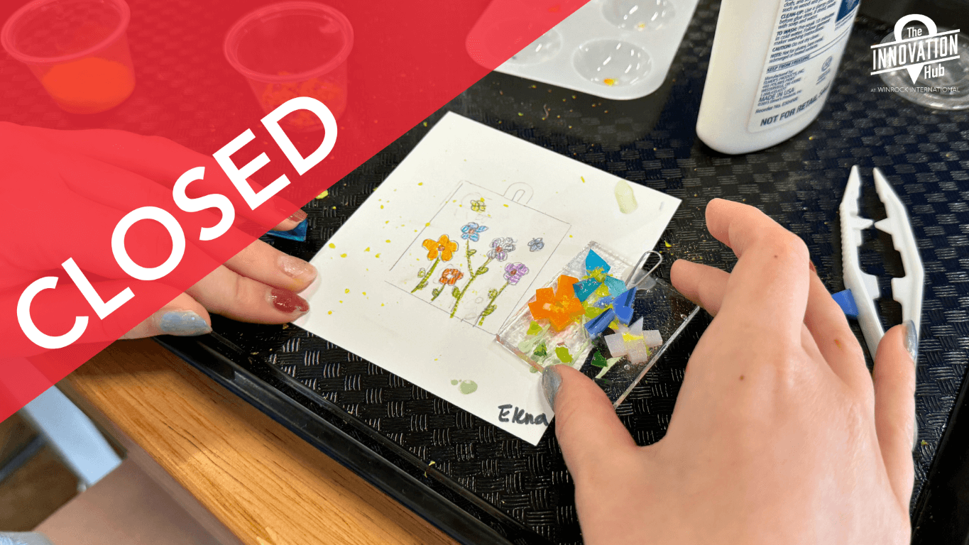 A young girl compares her fused glass art panel to her original sketch of brightly colored flowers.